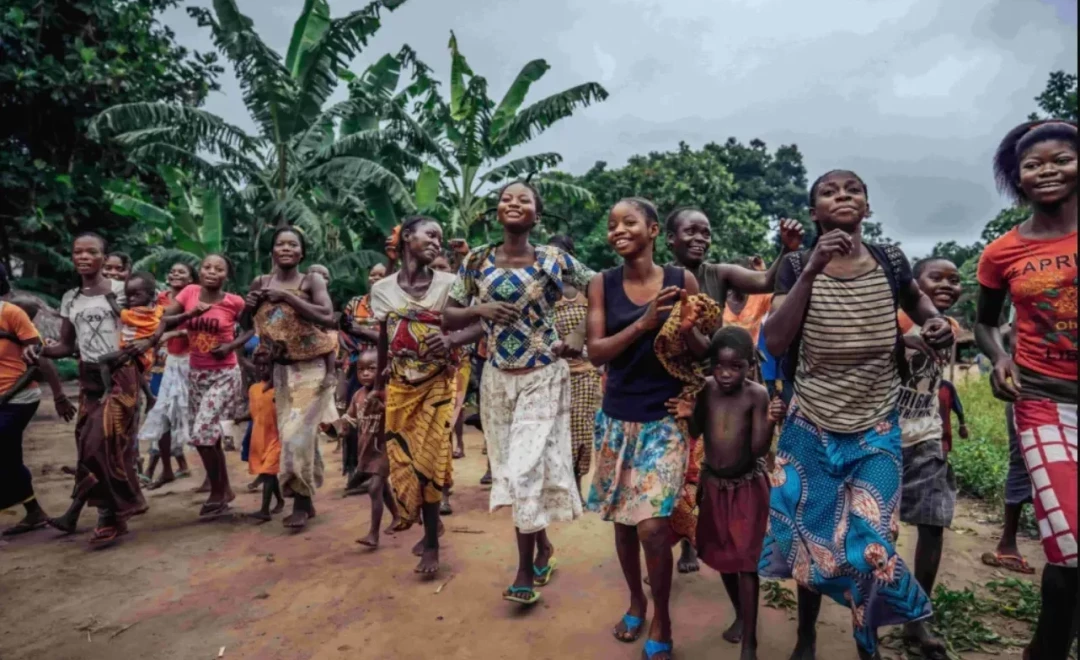 Community members walking together beneath banana trees and forest